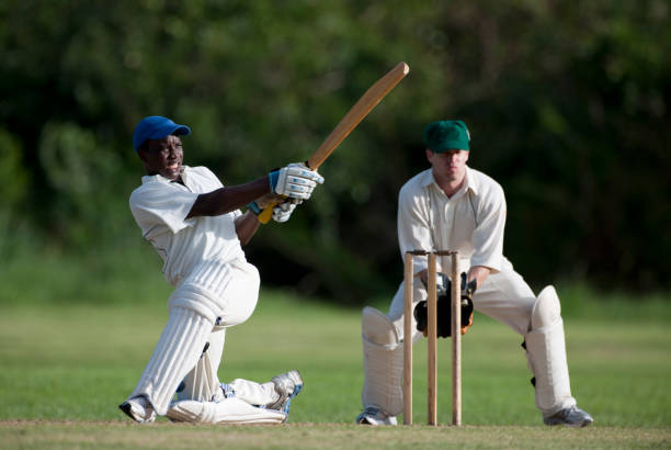 Cricket action, batsman playing a sweep shot watched by the wicketkeeper. cricbet99